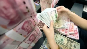 Çin’in Küresel Finans Sistemine Yeni Hamlesi: Doların Hegemonyası Sarsılıyor mu?

İÇERIK:
Çin, küresel finans sisteminde **doların hakimiyetini azaltmaya** yönelik uzun vadeli stratejisinde yeni bir aşamaya geçti. Şanghay’da açıklanan düzenlemelerle birlikte **yuanın uluslararası kullanımının artırılması** hedeflenirken, Pekin yönetimi alternatif bir finansal mimari oluşturma yönündeki adımlarını hızlandırdı. Bu gelişme, küresel para sisteminde **güç dengelerinin yeniden şekillenebileceğine** dair beklentileri artırdı.
Çin’in Stratejisi Siyasiler, merkez bankacıları, yatırımcılar ve finans dünyasının önde gelen isimleri Çin’in en önemli finans etkinliklerinden biri olan Lujiazui Forumu için Şanghay’da buluşuyor. Bu yılki forumda Çin yönetimi, **denizaşırı yuan kullanımını artıracak**, **sınır ötesi ticarette yerel para birimini teşvik edecek** ve Şanghay’ın **küresel finans merkezi** rolünü güçlendirecek yeni adımlar açıkladı.
Ayrıca **yabancı merkez bankaları** ve **devlet yatırım fonları** için **yeni likidite imkanları** sunulması ve **finans sektörünün belirli alanlarının uluslararası yatırımcılara** daha fazla açılması planlanıyor. Çin yıllardır **yuanın uluslararası kullanımını artırmaya** çalışırken asıl hedefin **doların yerine geçecek yeni bir rezerv para yaratmak** değil, **küresel finans sistemindeki dolar bağımlılığını azaltacak alternatif kanallar** ve finansal altyapılar oluşturmak olduğu belirtiliyor.
Dolar Bağımlılığı ABD 80 yıldır **doların küresel finans sistemindeki merkezi konumundan** önemli avantajlar elde ederken, **yaptırımlar**, **uluslararası ödeme sistemlerine erişim sınırlamaları** ve **küresel sermaye akışının kontrolü** gibi hamlelerle ülkeleri kıskaca alıyor. Çin ise bu gücün tek merkezde toplanmasının yarattığı stratejik riskleri uzun süredir yakından takip ederken **20 yıldır sürdürdüğü yuanın uluslararasılaşması stratejisini** yeni bir aşamaya taşıdı.
**Doların hakimiyetini kısa vadede sona erdiremeyeceğinin** farkında olan Pekin, uzun vadede ülkelerin ve yatırımcıların sadece **dolar merkezli bir sisteme** bağımlı kalmayacağı **alternatif bir finansal mimari** inşa ediyor. **2008 küresel finans krizinin** ardından yerel para birimiyle **ticaret**, **swap anlaşmaları** ve **alternatif ödeme sistemleri** gibi uygulamaları devreye alan Çin, **Beş Yıllık Kalkınma Planı**’nda da **finans sektörünü** stratejik öncelik arasında belirledi.
Pekin yönetimi, Çin’i **küresel bir finans merkezi** haline getirmeyi, **denizaşırı yuan piyasalarını büyütmeyi** ve **sınır ötesi ödeme altyapısını** geliştirmeyi hedefliyor. Bu **gelişmeler**, **küresel finans sisteminin geleceğine** dair önemli **projeksiyonları** ve **beklentileri** içeriyor.